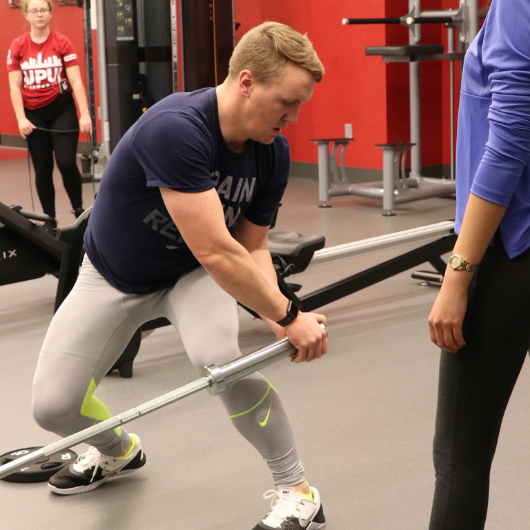 Man does weight training in a gym.