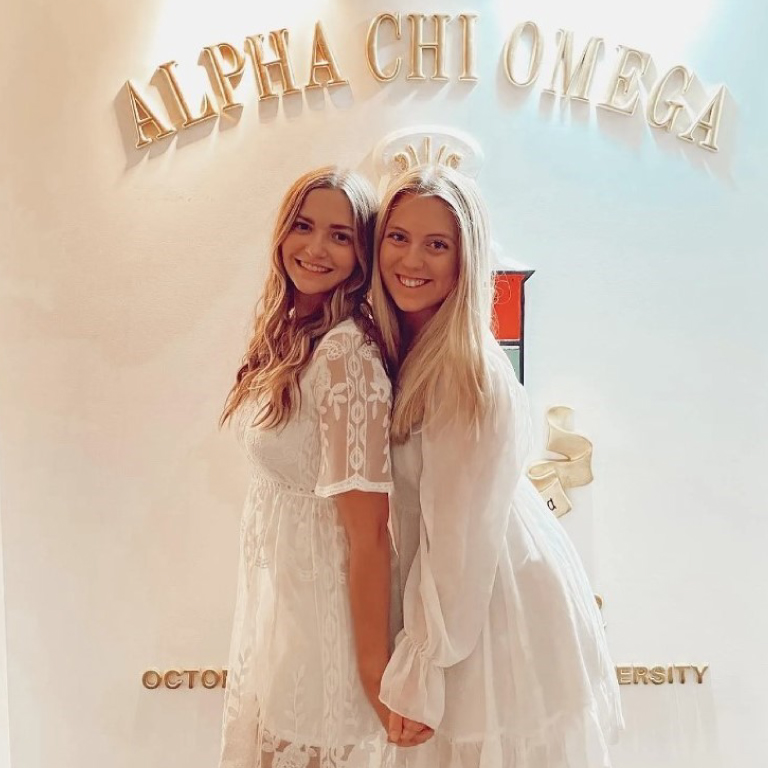 Two of the sorority members smiling and holding hands.