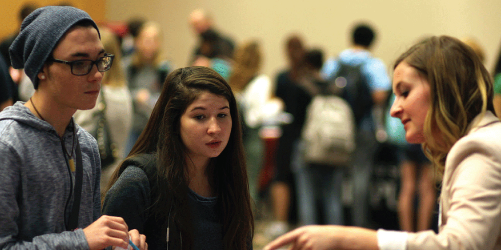 Students talk with someone tabling at a job fair on campus.