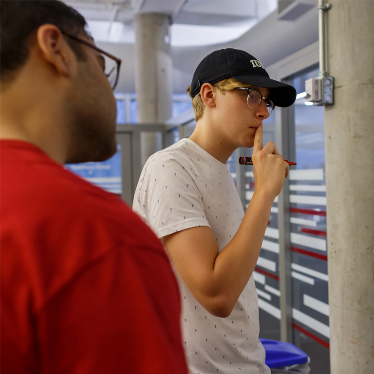 Students create a plan using a white board in the cube