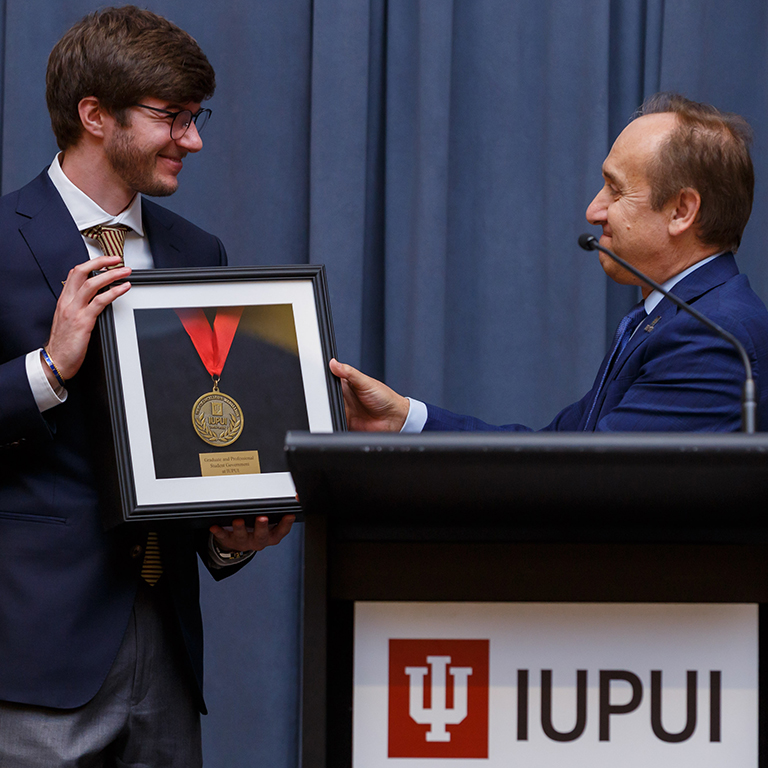 A student is presented an award by Chancellor Nasser Paydar.