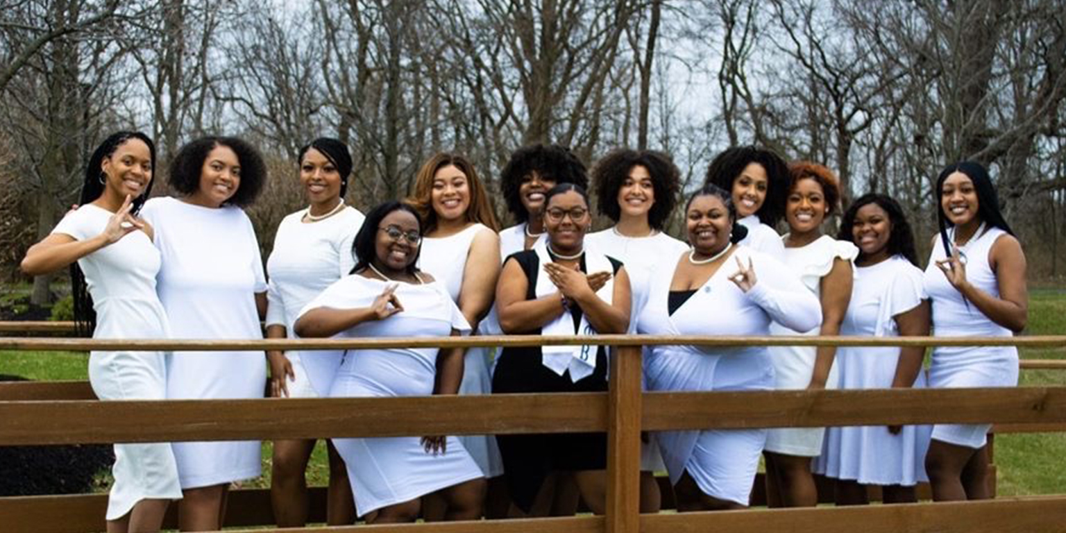 Members of Zeta Phi Beta Sorority, Inc. wearing white dresses and posing for a photo.
